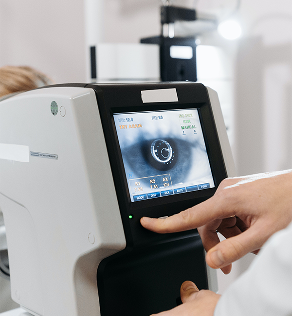 eye examination, a girl is looking at a eye diagnostics machine and a doctor is looking at a eye diagnostics machine screen